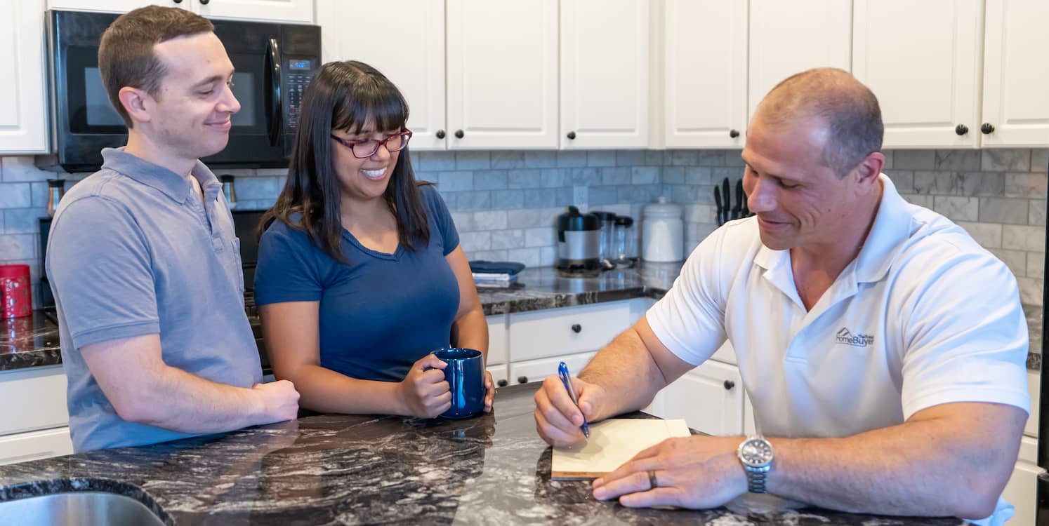 man giving a young couple a loan in their kitchen